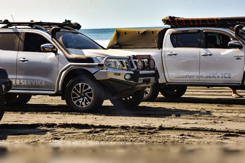 Dos camionetas con la marca Super Service en una playa